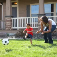 Boy and Mom playing soccer in grass